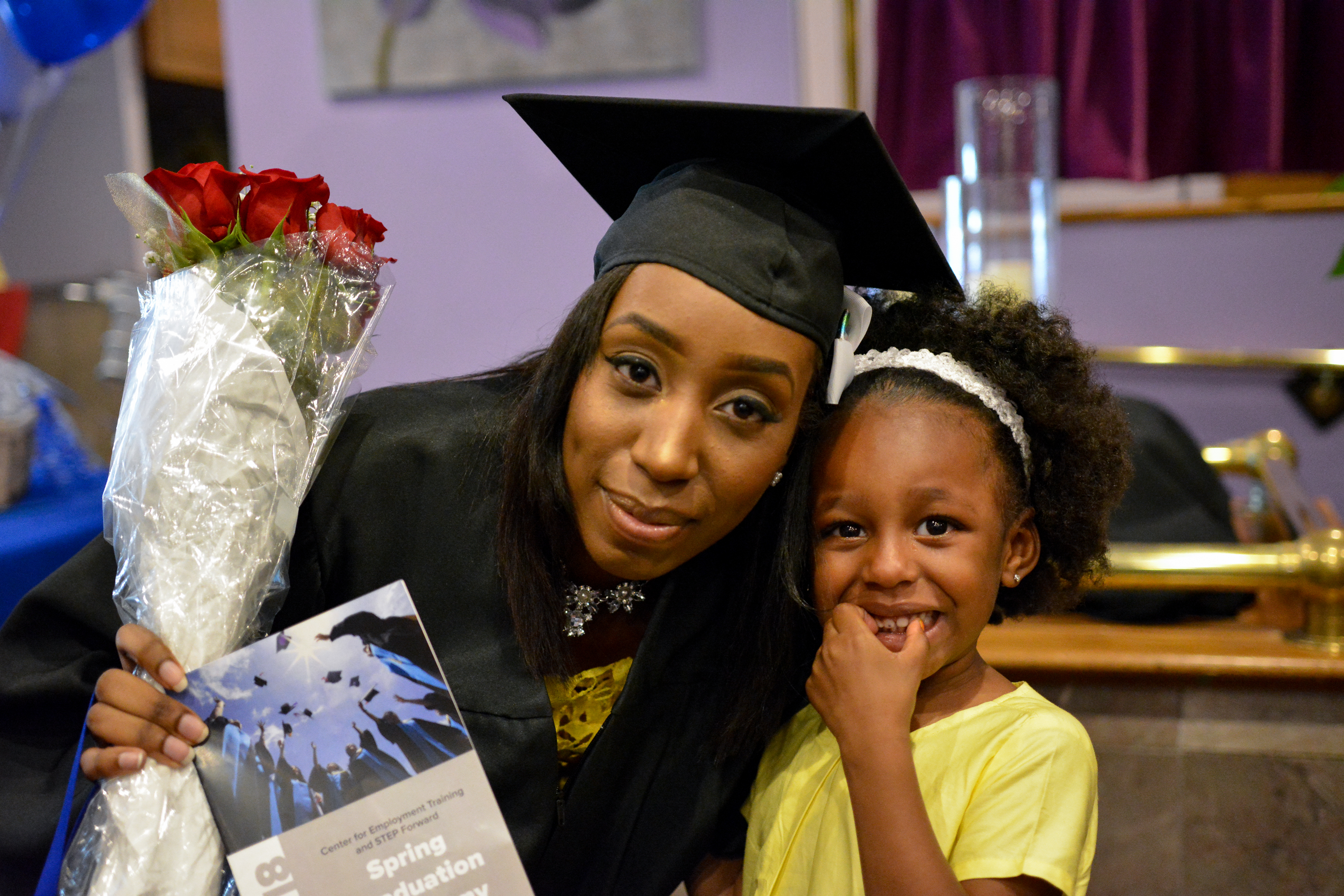 Trainee posing with child at CET Spring Graduation Ceremony.